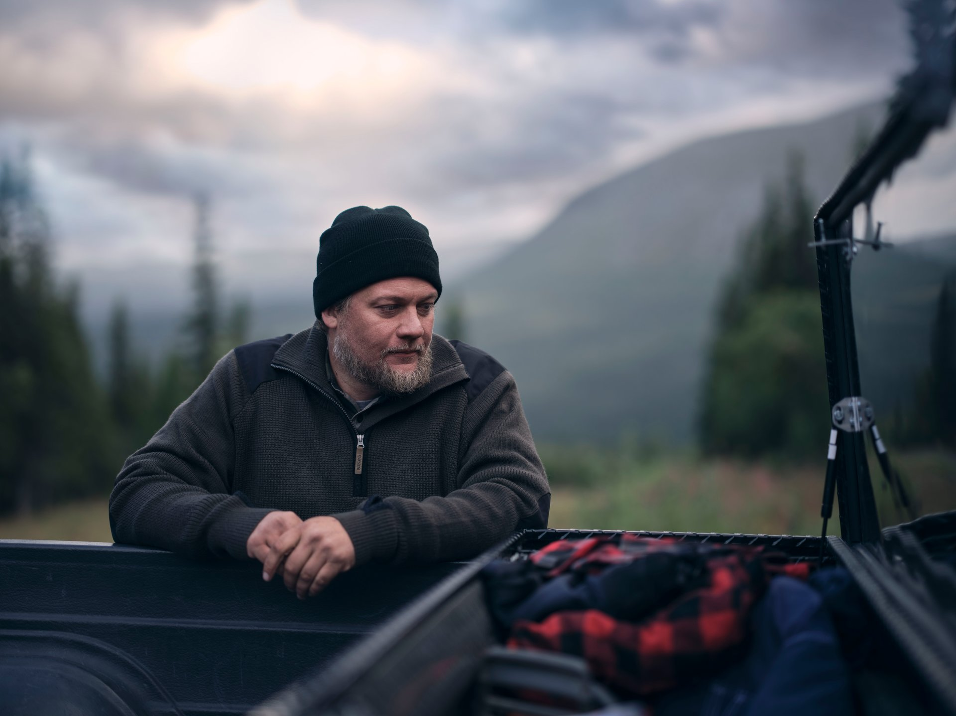 Man sitting in the back of a truck with mountains in the background